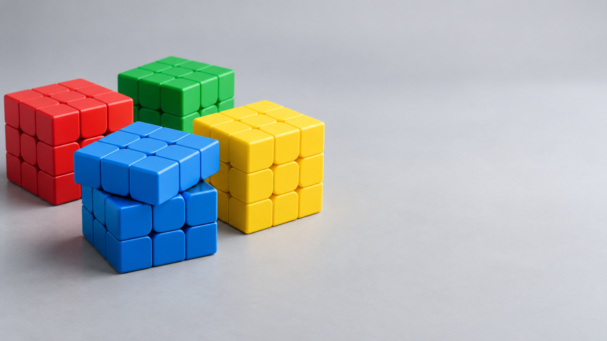 Four stickerless 3x3 speed cubes in red, green, blue, and yellow on a light gray surface, one with its top layer mid-turn